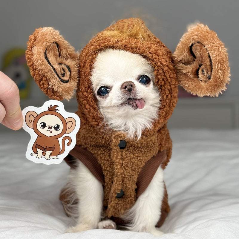Small dog wearing a brown monkey costume with a sticker of a monkey on a white surface.
