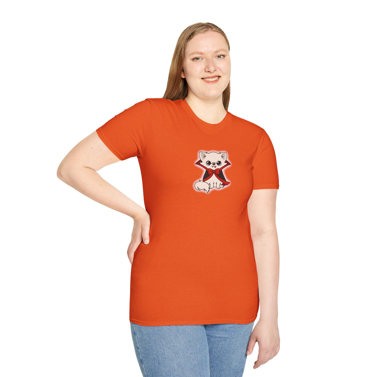 Person shown from behind wearing an orange t-shirt with a small round graphic centered below the neckline on the back, featuring Cedric the cream chihuahua in a black cape with red accents inside a yellow circle.