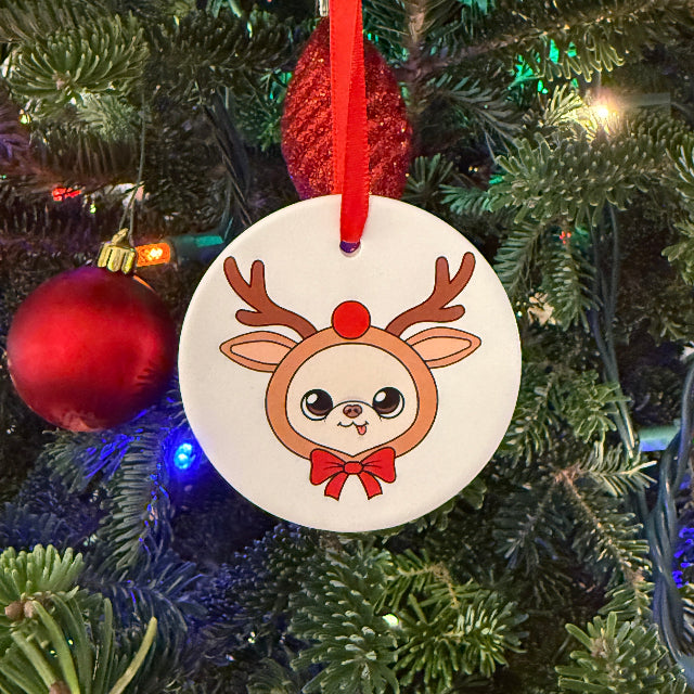 Circular ornament with a reindeer design on a Christmas tree.