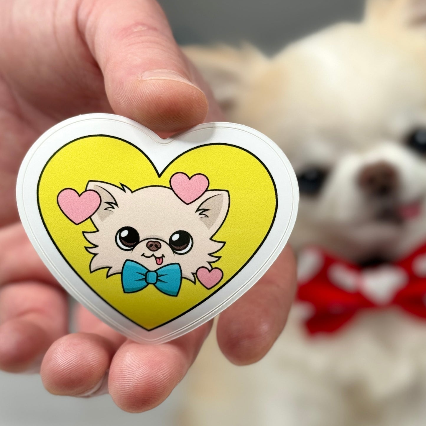 Close-up of Cedric's Cheerful Heart Sticker, prominently featuring a vibrant yellow heart surrounded by pink hearts, with a slightly out-of-focus Cedric in the background, symbolizing a joyful and loving atmosphere.