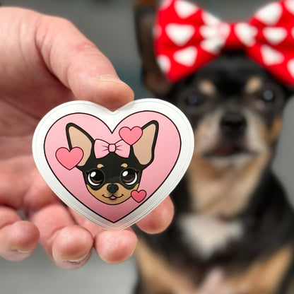 Close-up of Maya's Happy Heart Sticker, featuring a prominent pink heart surrounded by smaller pink hearts, with a slightly out-of-focus Tiny Chihuahua Maya in the background, adorned with a heart bow on her head, symbolizing warmth and affection.