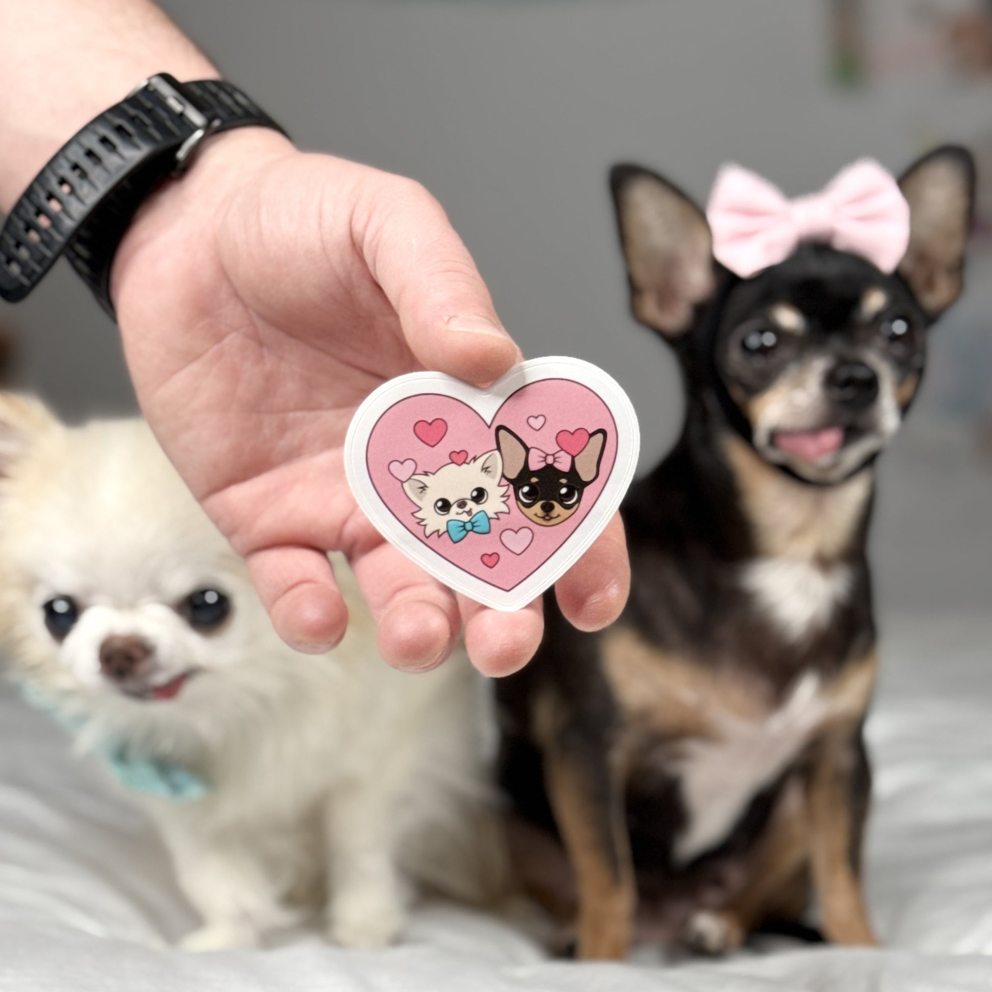 Close-up of a heart-shaped sticker featuring Cedric and Maya with playful expressions and a pink background surrounded by hearts.