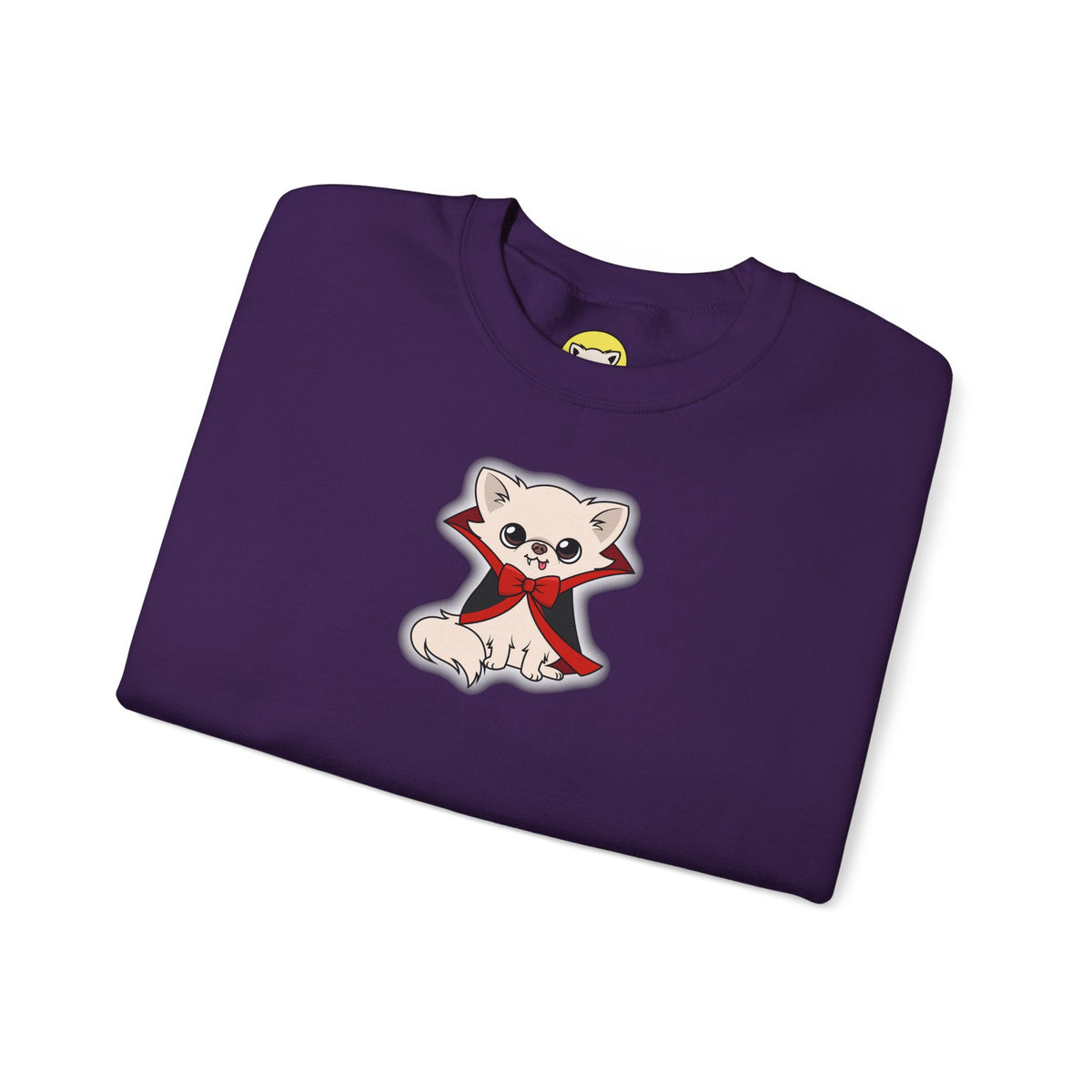 Folded purple crewneck sweatshirt featuring a cream chihuahua named Cedric sitting in a black cape with red lining and a red bow, outlined by a soft white glow on the chest.