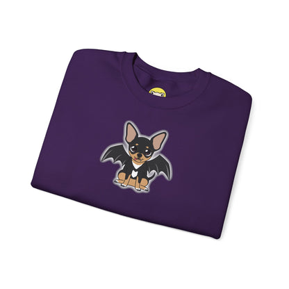 Folded purple crewneck sweatshirt with a cartoon black-and-tan chihuahua on the front, shown with bat wings, a white chest marking, and a small fang, outlined by a soft gray glow.