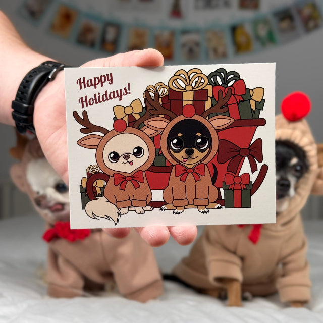 Person holding a Christmas card with cartoon reindeer and gifts, with a dog in a costume in the background.