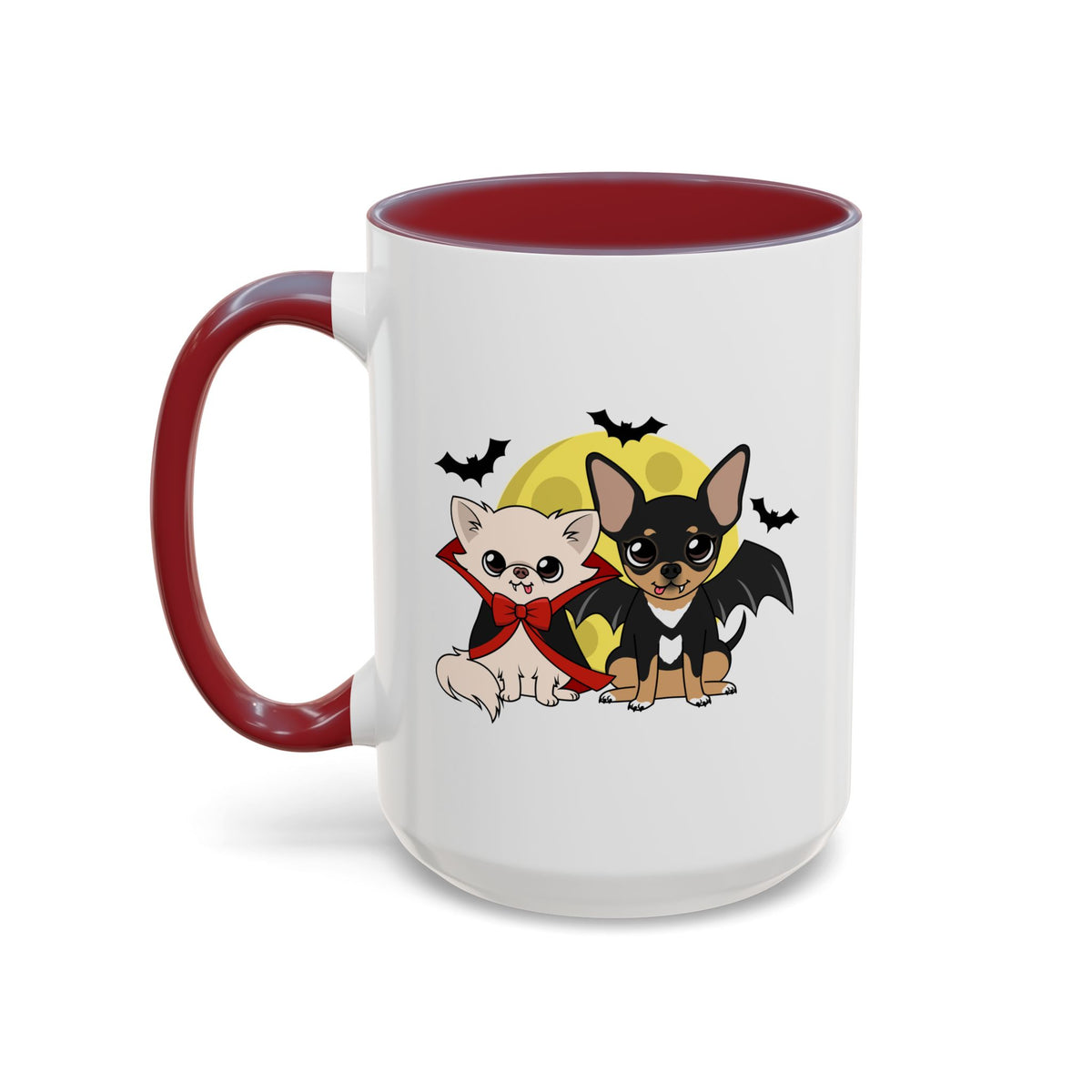 White coffee mug with maroon handle and interior, featuring two cartoon chihuahuas in front of a yellow moon and small bats, one cream dog in a red cape and bow and one black-and-tan dog with bat wings.
