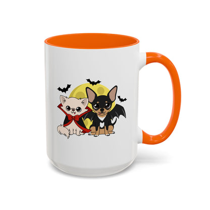 White mug with orange handle and interior, featuring a cream chihuahua in a red cape and bow and a black-and-tan chihuahua with bat wings sitting together before a yellow moon and flying bats.