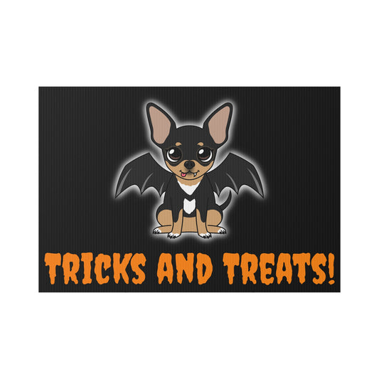 Rectangular black lawn sign with a cute black-and-tan chihuahua named Maya in the center, shown with bat wings, a small white chest marking, a single little fang and a soft white glow around her, with the words “TRICKS AND TREATS!” in bold orange lettering along the bottom.