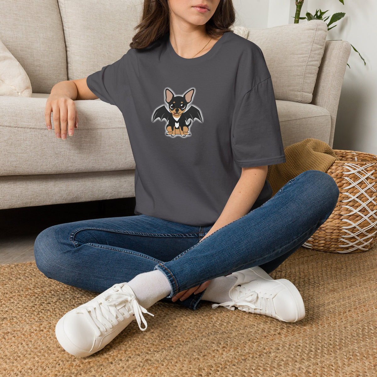 Femme assise à l’intérieur, portant un t-shirt gris charbon à motif Vampire Maya.