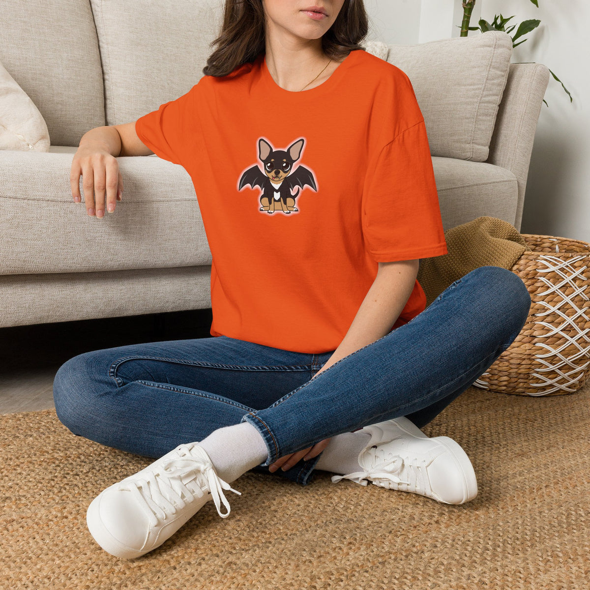 Femme assise à l’intérieur, portant un t-shirt orange à motif Vampire Maya.