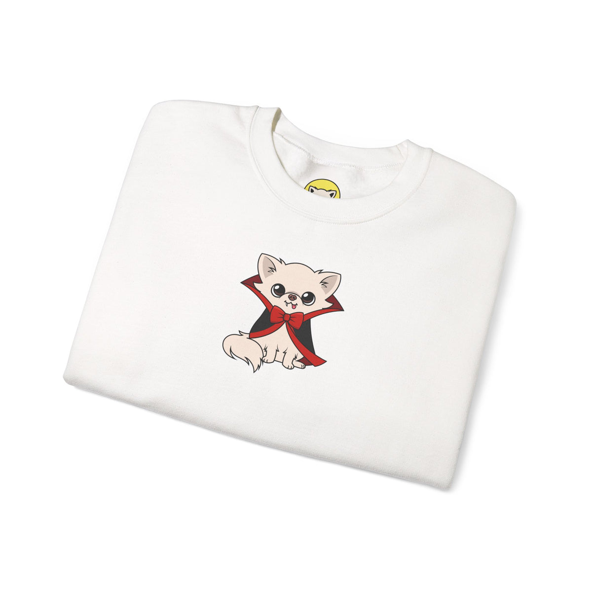 Folded white crewneck sweatshirt featuring an illustration of Cedric, a cream chihuahua sitting in a black cape with red lining and a red bow tie on the front center.